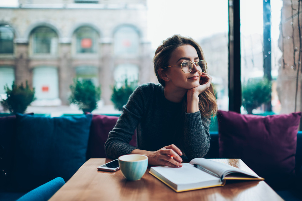 Woman at cafe reading a B2B client relationships book